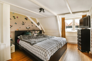 a bedroom with a bed, dressers and tv in the corner on the wall above the bed is an image of birds...