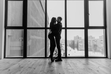 Smiling and lovely multiethnic couple tenderly hug on balcony
