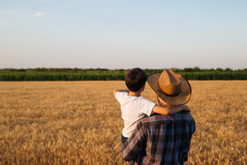 Naklejka na ściany i meble Father and son looking at their wheat field together