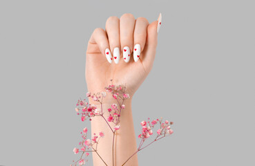 Female manicure one hand with gypsophila flowers gel polish white long nails and red hearts desing...