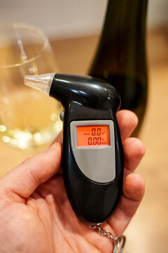 Man holds an alcohol tester in his hand.