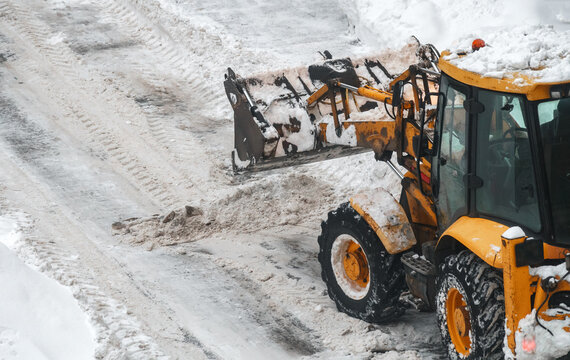 Tractor shoveling snow on the street.