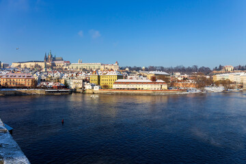 Fototapeta premium Sunny snowy Prague Lesser Town with gothic Castle from Charles Bridge, Czech republic