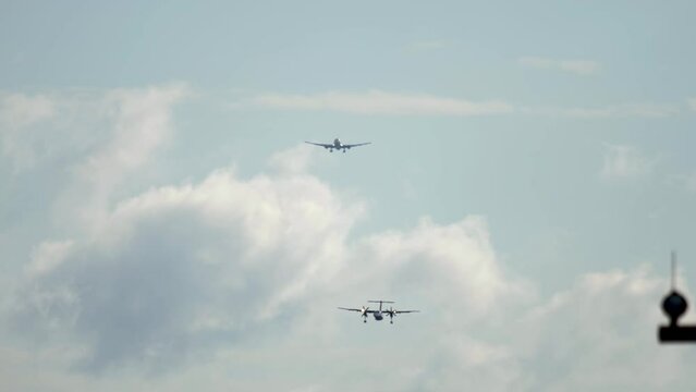 Passenger turboprop plane approaching airport for landing, front view. Line of planes in the sky. Tourism and travel concept
