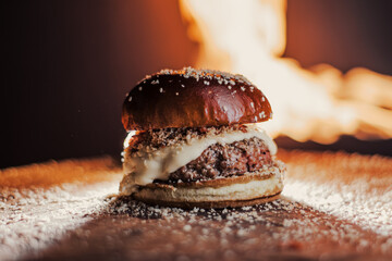 
Delicious hamburger, with homemade meat, lots of cheese and bacon, with a black background and fire scene.