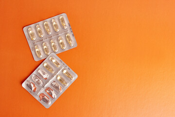 Vitamins in the form of capsules on an orange background. Treatment and prevention of diseases. Strengthening immunity.