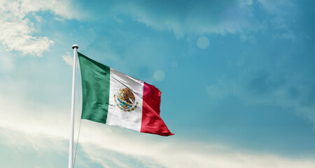 Waving Flag of Mexico in Blue Sky. The symbol of the state on wavy cotton fabric.