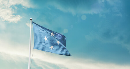Waving Flag of Micronesia in Blue Sky. The symbol of the state on wavy cotton fabric.