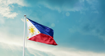Waving Flag of Philippines in Blue Sky. The symbol of the state on wavy cotton fabric.