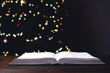 An open Bible on the table. On the background of the Christmas tree. Christmas service. Christmas...