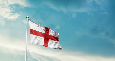 Waving Flag of England in Blue Sky. The symbol of the state on wavy cotton fabric.