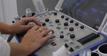 Close-up on the buttons and sensors on the ultrasound machine. Warcha's hands press buttons and turn knobs as they take measurements and examine survey data.