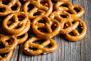 Salty mini party pretzels on a wooden surface close-up.