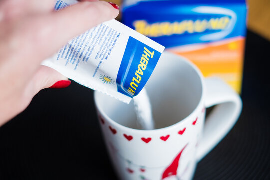 Tallinn, Estonia - December 16, 2022: Theraflu tea powder for flu treatment. Making flu or common cold medicine at home.