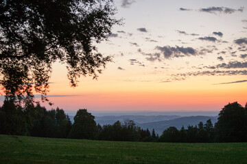 At sunrise, the sky changes color above the hills and trees in Sumava's Bohemian forest.; Bohemian forest, Sumava, Czech Republic