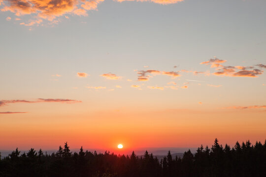 At sunrise, the sky and clouds change color above the trees in Sumava's Bohemian forest.; Bohemian forest, Sumava, Czech Republic