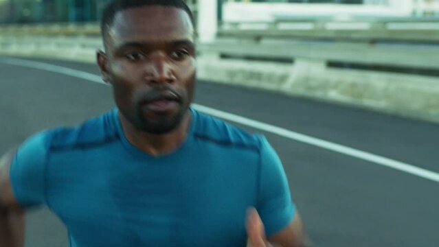 Black man, running and speed with fitness on city bridge, exercise and focus with energy. Training for marathon, triathlon or race. Challenge, runner in street with sports workout and sweat outdoor.