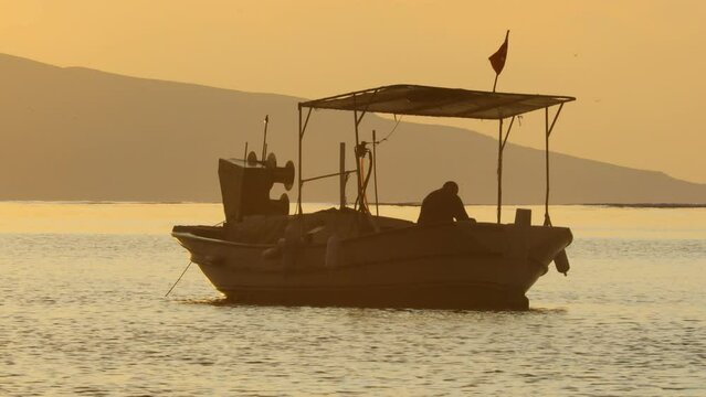 At sunset, the fisherman pulls the chain of his boat out of the sea. silhouette image.	
