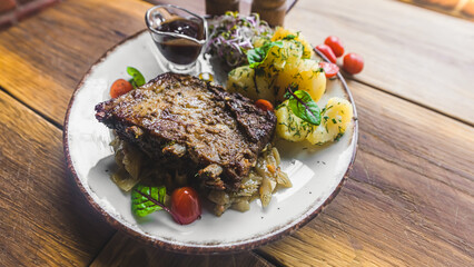 Traditional Polish meat dish - pork ribs served with boiled potatoes and seasonal vegetables. Wooden table as a background. High quality photo