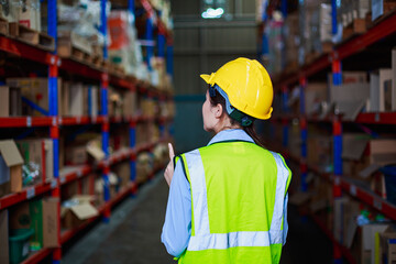 young asian women worker wearing hard hat checks products stock and Inventory with Digital tablet standing in retail warehouse factory full of Shelves with Goods. logistics transportation concept	