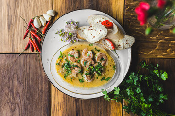 Seafood dish. Prawns cooked in spicy sauce with three pieces of bread served on white plate. Decoration of parsley, garlic cloves, and chili peppers. High quality photo