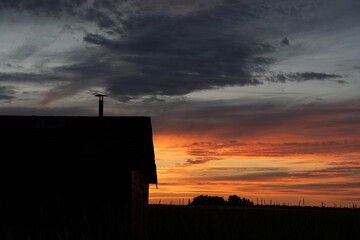 Rustic barn silhouette under a sunset sky prairie landscape in Rocky View County Alberta Canada.