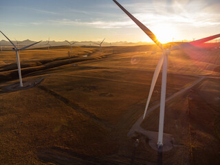 Aerial windmills at sunset with sun rays producing sustainable energy on the Alberta prairies in Canada.