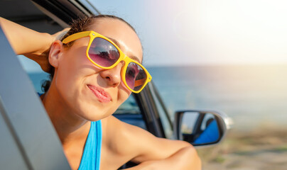 Beautiful girl in a car smiling on a background of blue sea.