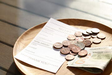 Wooden plate with payment for order and receipt on table, closeup. Leave tip