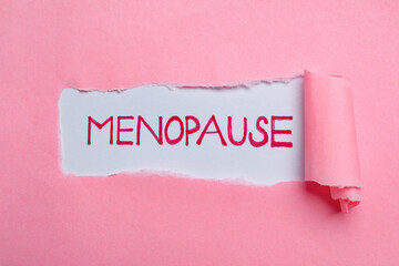 Word Menopause written on white background, view through hole in pink paper