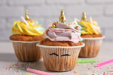 Cute sweet unicorn cupcakes on beige table, closeup
