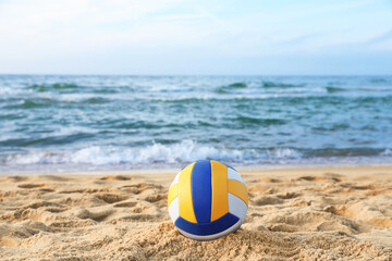 Colorful volleyball ball on sand near sea
