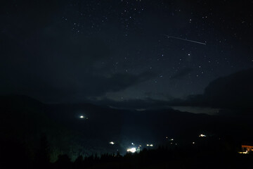 Picturesque view of small town in mountains and beautiful starry sky at night