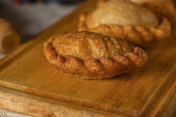 Close up of fried Argentine empanadas on a wooden board.