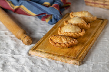 Fried Argentine empanadas on a wooden board.