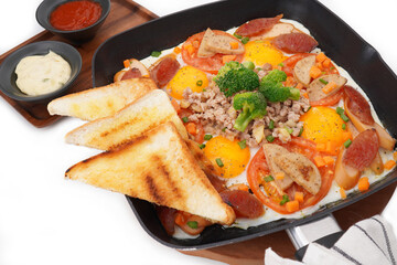 Fast food breakfast, fried eggs in pan and vegetables, top view.