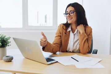 Business woman working in the office at her desk with a laptop, smile and business dialogue via video link, hand gestures in dialogue, online communication