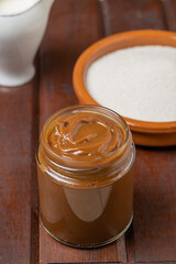 Dulce de leche, traditional sweet from Argentina, sugar and milk on wooden table.