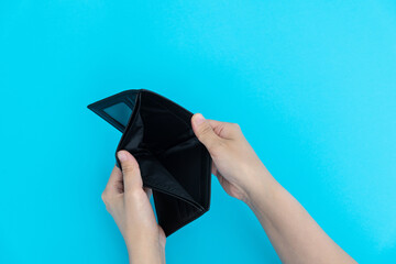 Woman hand open an empty wallet on blue background