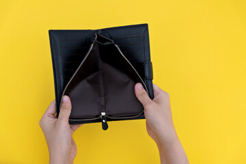 Woman hand open an empty wallet on yellow background
