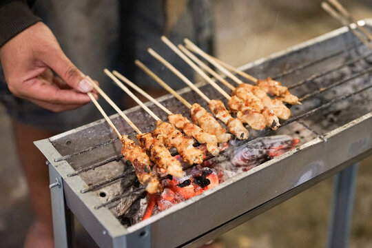 Sate ayam or chicken satay with charcoal ingredient on red fire charcoal grilling, cooking satay.