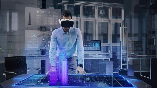 Professional Male Architect wearing Augmented Reality Headset makes gestures and redesigns 3D City Model. High Tech Office use Virtual Reality Modeling Software Application.