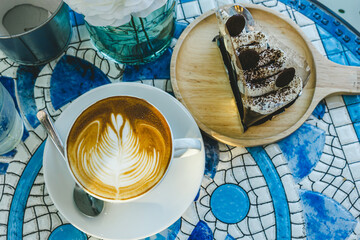 Merry x-mas,Hot coffee latte with latte art milk foam in cup mug and Homemade chocolate cake with Xmas decors and Xmas tree baubles on marble floor desk Celebrating Merry Christmas and New year.