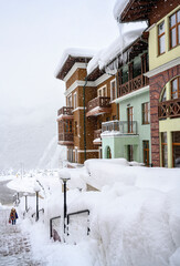 The street of the Krasnaya Poliana ski resort in snowstorm on the background of mountains in the...
