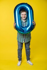 boy with a balloon. cheerful guy holding a number from zero to 9. yellow background