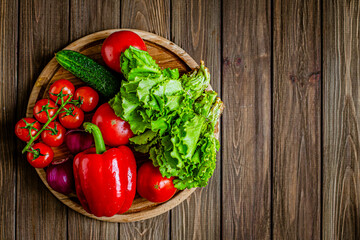 Top down view of close-up still life of fresh vegetables and herbs on wooden table, free space 