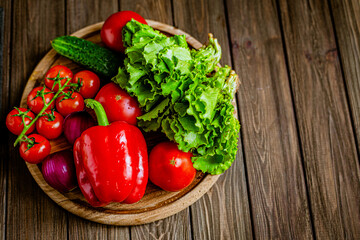 Top view of close-up still life of fresh vegetables and herbs on wooden table, free space 