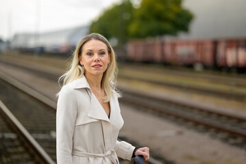 Fototapeta premium Woman in a white trench coat in front of train wagons