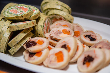 Sliced appetizer roll with greens, cheese and fish on a plate. Butter roll with dried apricots and prunes. food for the holiday