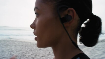 Fitness, exercise and woman with earphones at the beach listening to music, radio and audio for workout. Running, healthy lifestyle and profile of girl with headphones for marathon training by ocean